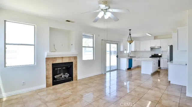 a view of kitchen and empty room with fireplace