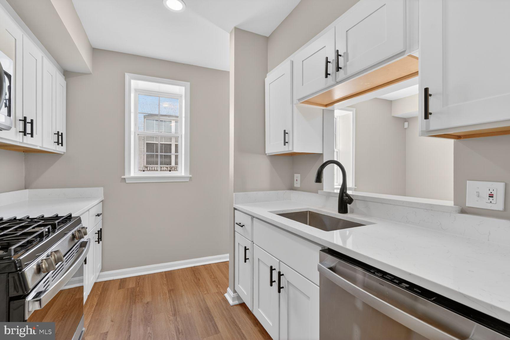 1008 Rittenhouse Street Northwest, Unit 15 Washington, DC 20011 - Photo 12 of 39 a kitchen with granite countertop a sink cabinets a stove and wooden floor