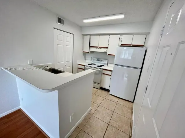 a kitchen with a sink a refrigerator a counter top space and cabinets