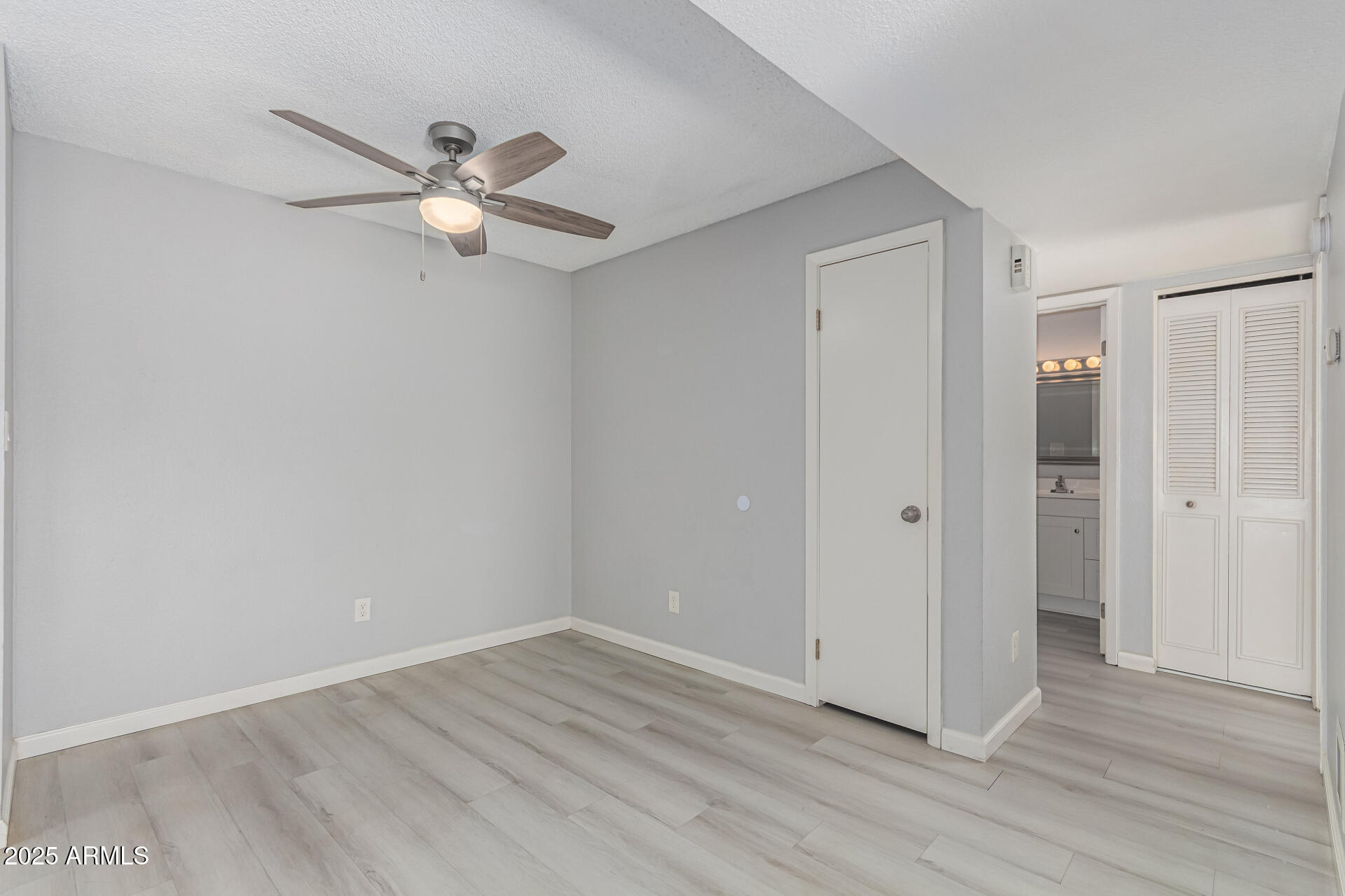 4730 West Northern Avenue, Unit 1087 Glendale, AZ 85301 - Photo 18 of 34 an empty room with wooden floor fan and windows