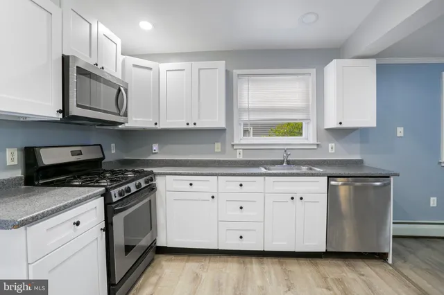 a kitchen with granite countertop white cabinets and stainless steel appliances