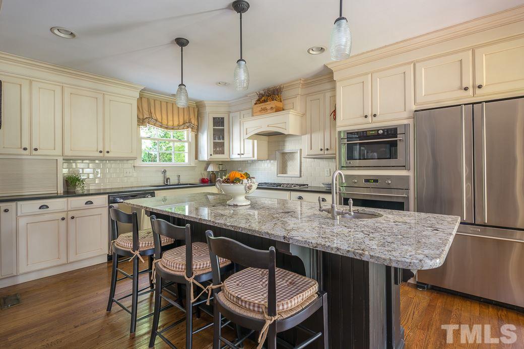 3104 Georgian Terrace Raleigh, NC 27607 - Photo 8 of 25 a kitchen with stainless steel appliances granite countertop a kitchen island stools a stove a dining table and chairs