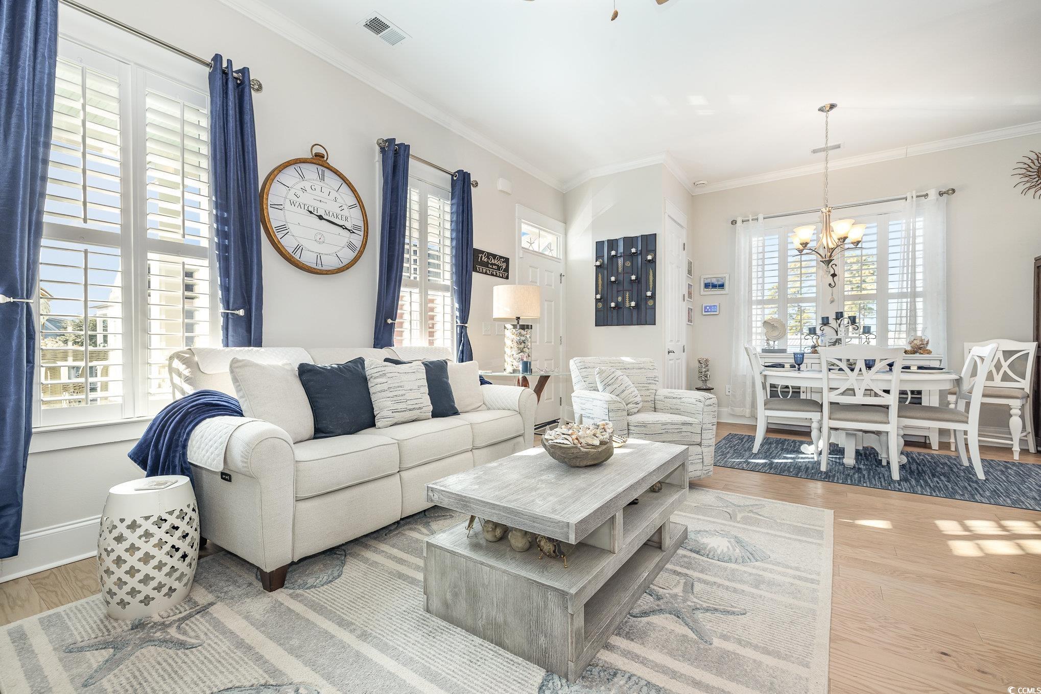 Living room with crown molding, a chandelier, and
