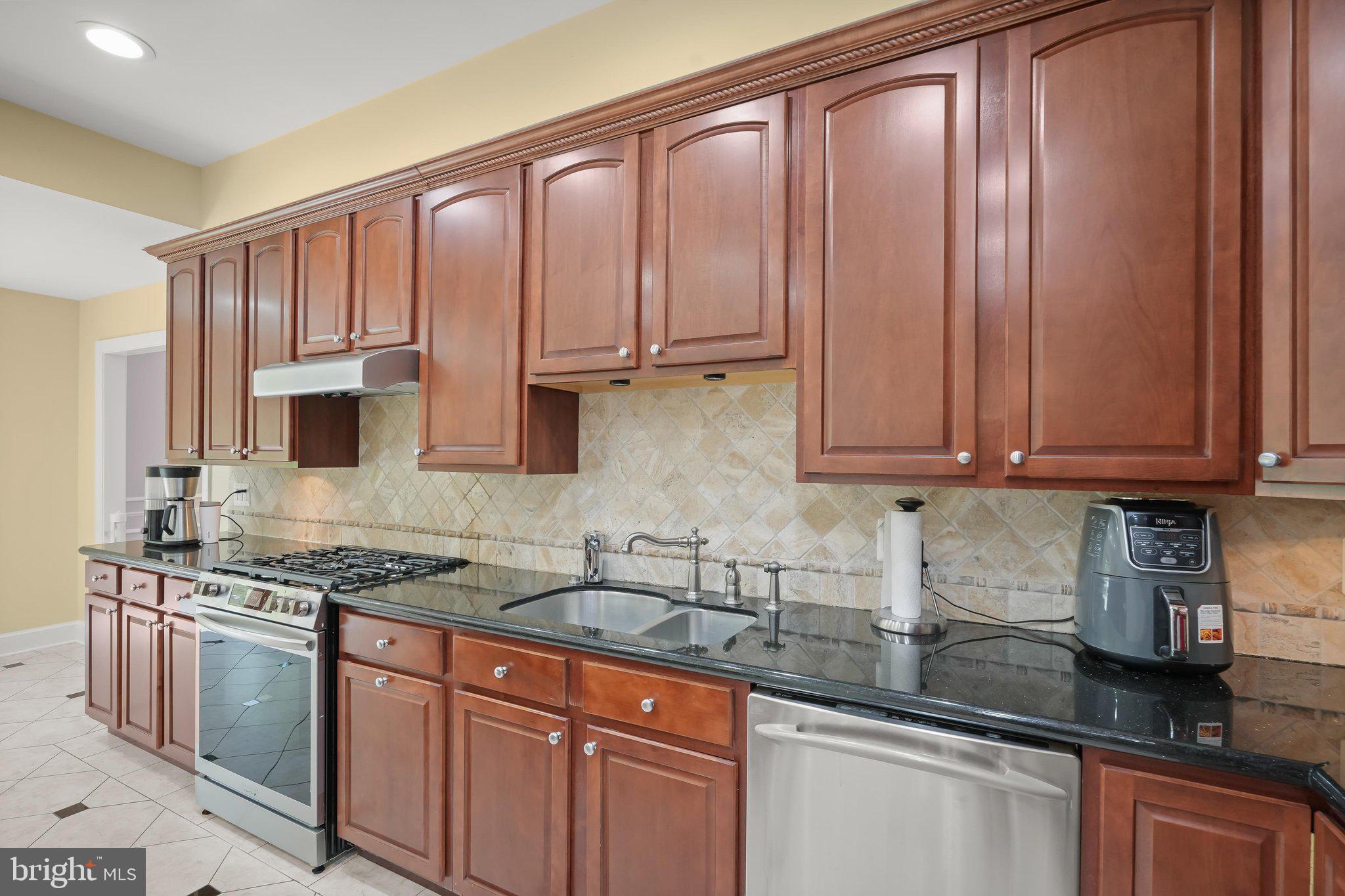 9809 Hall Road Potomac, MD 20854 - Photo 14 of 60 a kitchen with stainless steel appliances granite countertop a sink stove and cabinets