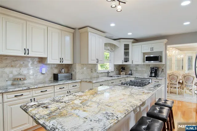 a kitchen with kitchen island granite countertop a sink stove and cabinets