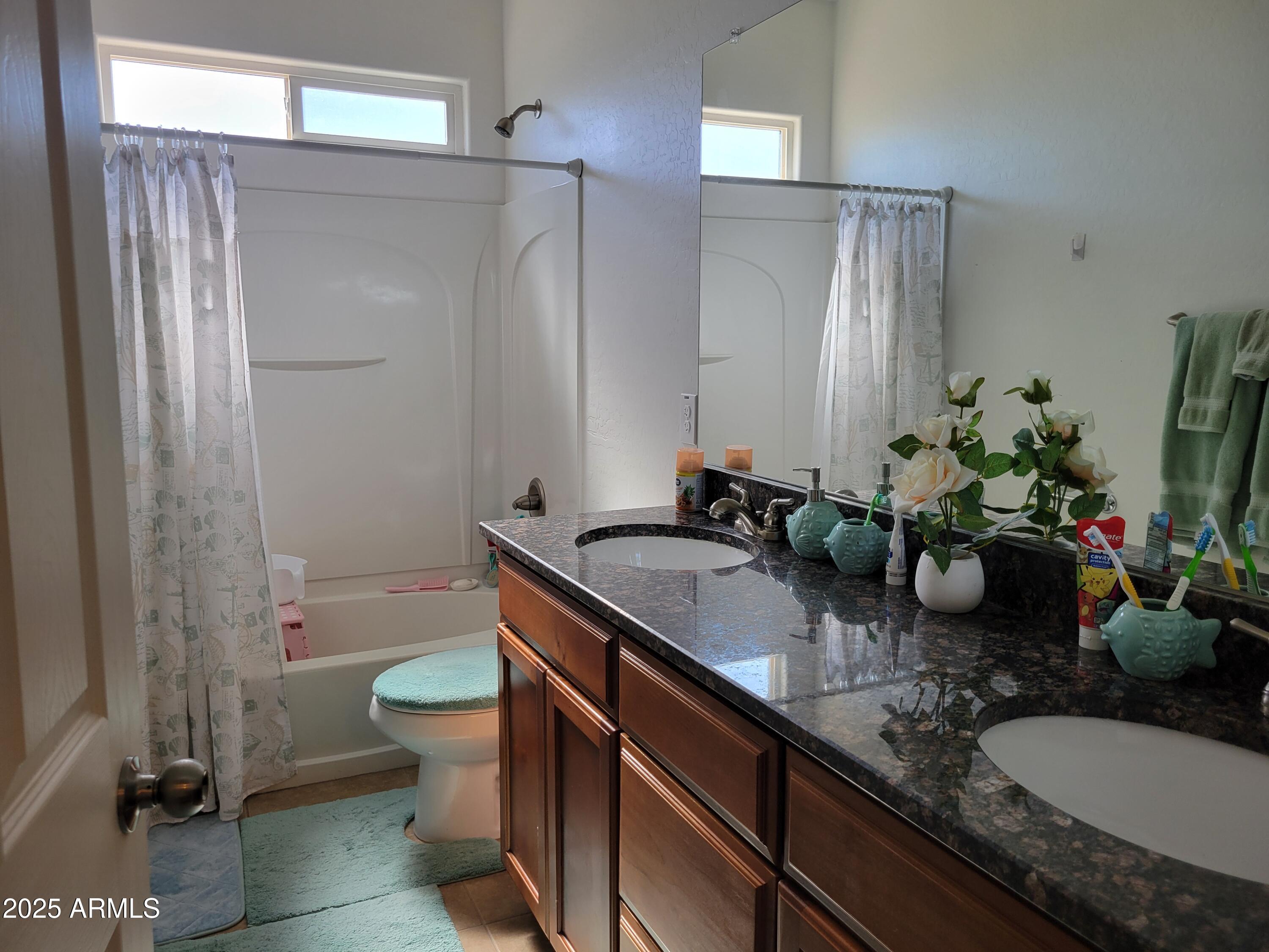 7439 West Wolf Street Phoenix, AZ 85033 - Photo 16 of 21 a bathroom with a granite countertop sink a toilet a mirror and shower