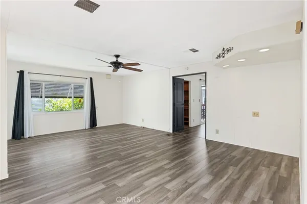 a view of an empty room with window and wooden floor