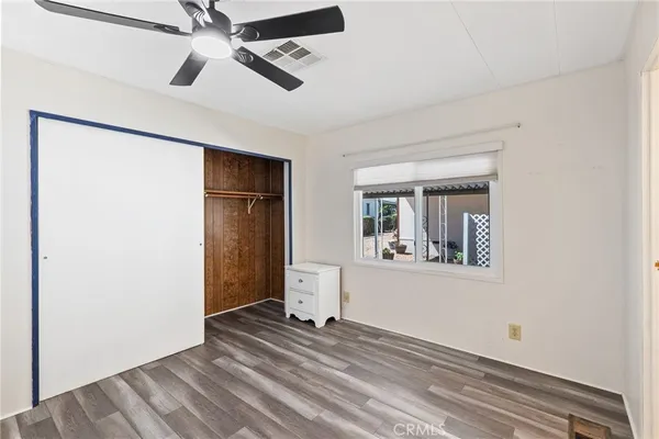 an empty room with wooden floor chandelier fan and windows