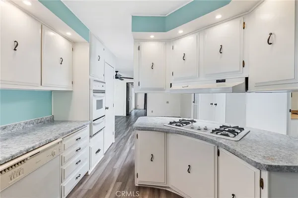 a kitchen with stainless steel appliances white cabinets and wooden floors