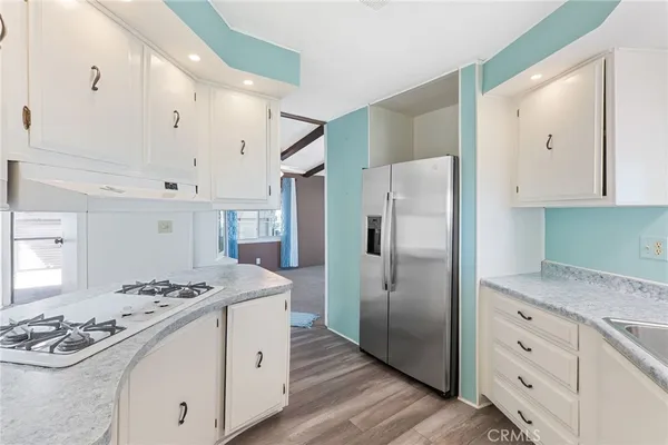 a kitchen with stainless steel appliances granite countertop a refrigerator stove a sink dishwasher and white cabinets with wooden floor