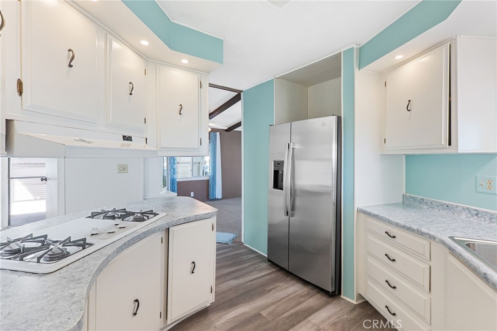 27701 Murrieta Road, Unit 227 Menifee, CA 92586 - Photo 10 of 36 a kitchen with stainless steel appliances granite countertop a refrigerator stove a sink dishwasher and white cabinets with wooden floor
