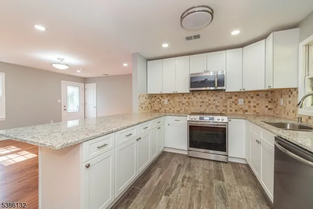 a kitchen with granite countertop a sink stainless steel appliances and cabinets