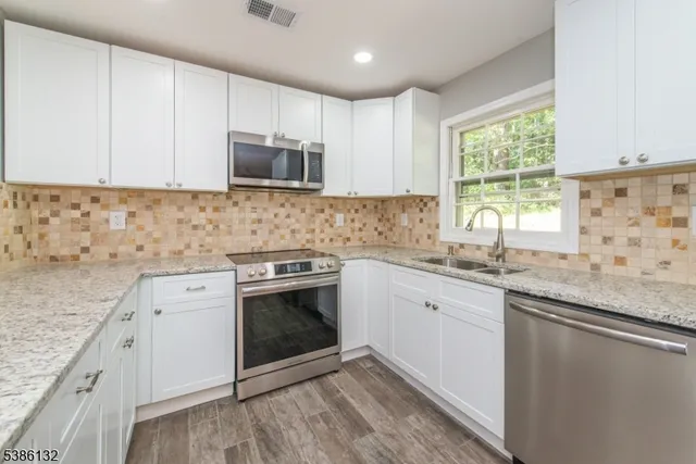 a kitchen with granite countertop stainless steel appliances white cabinets granite counter tops and a window