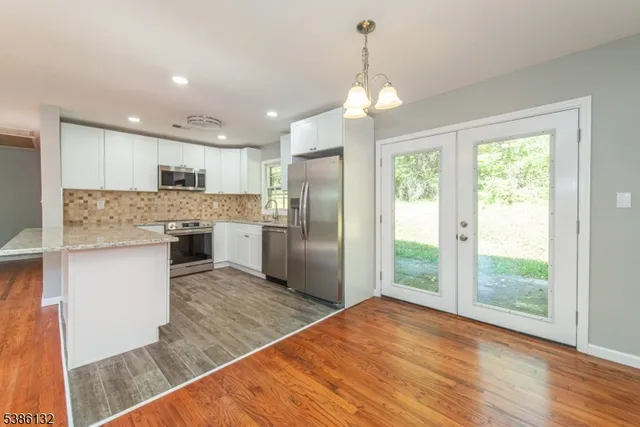 a kitchen with stainless steel appliances granite countertop a refrigerator a stove a sink dishwasher and a refrigerator with wooden floor