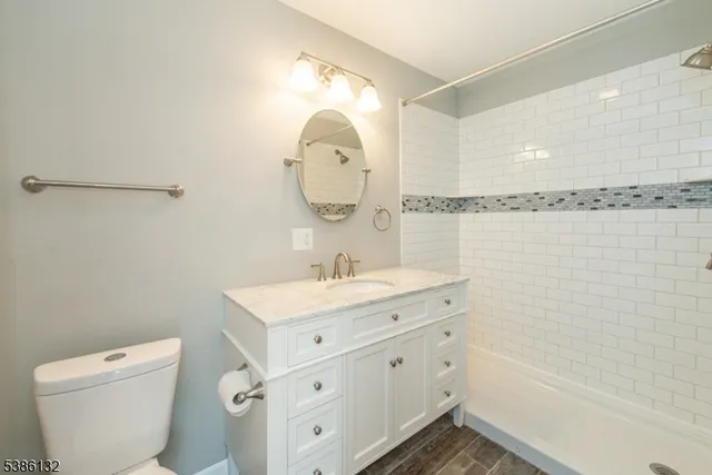 a bathroom with a granite countertop sink a toilet and a mirror