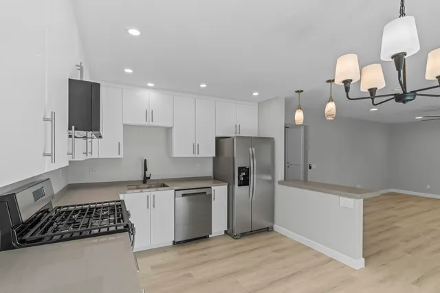 a kitchen with stainless steel appliances granite countertop a sink a stove a refrigerator and cabinets