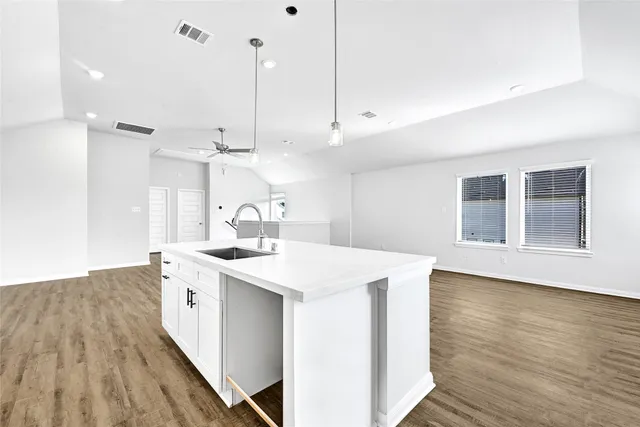 a kitchen with a sink a stove cabinets and wooden floor