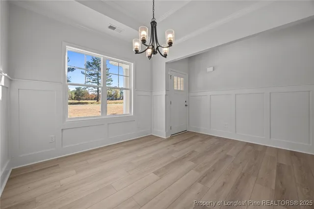a view of an empty room with window and chandelier fan