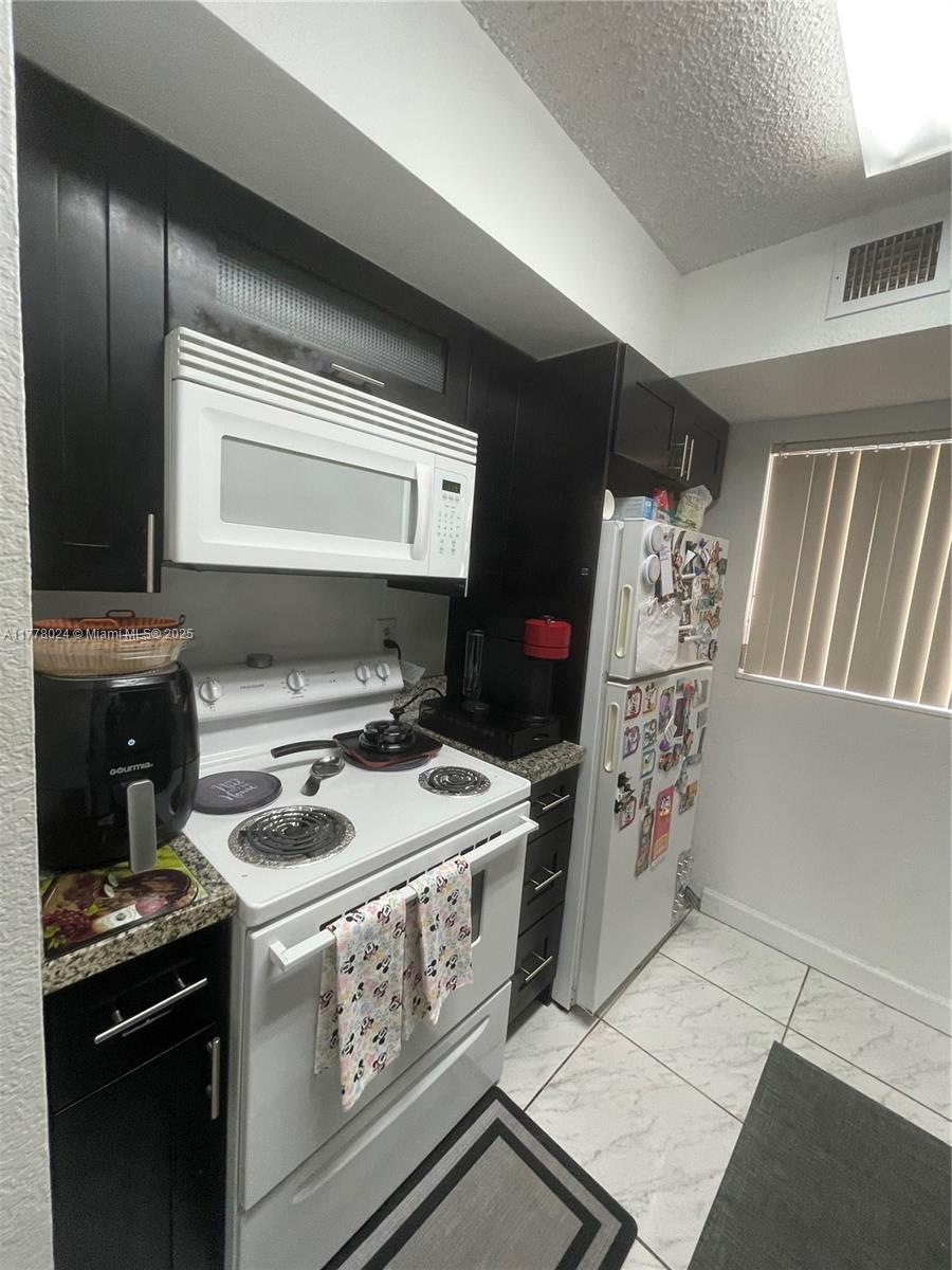 18230 Mediterranean Boulevard, Unit 1302 Hialeah, FL 33015 - Photo 12 of 42 a kitchen with stainless steel appliances granite countertop a stove and a refrigerator