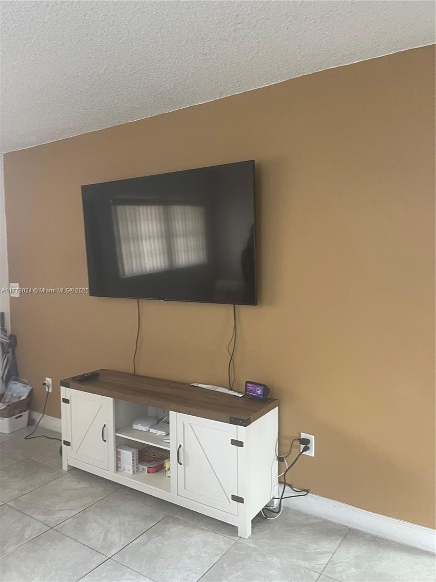 18230 Mediterranean Boulevard, Unit 1302 Hialeah, FL 33015 - Photo 14 of 42 a room with a flat screen tv and lamp