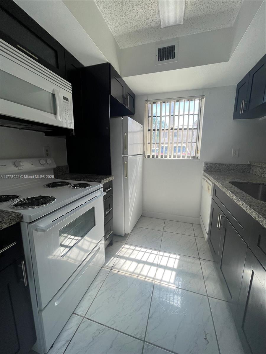 18230 Mediterranean Boulevard, Unit 1302 Hialeah, FL 33015 - Photo 21 of 42 a kitchen with a stove a refrigerator and cabinets