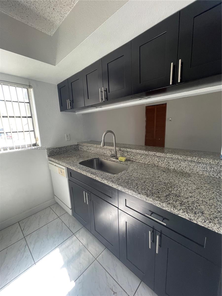 18230 Mediterranean Boulevard, Unit 1302 Hialeah, FL 33015 - Photo 22 of 42 a kitchen with granite countertop a sink a stove and cabinets