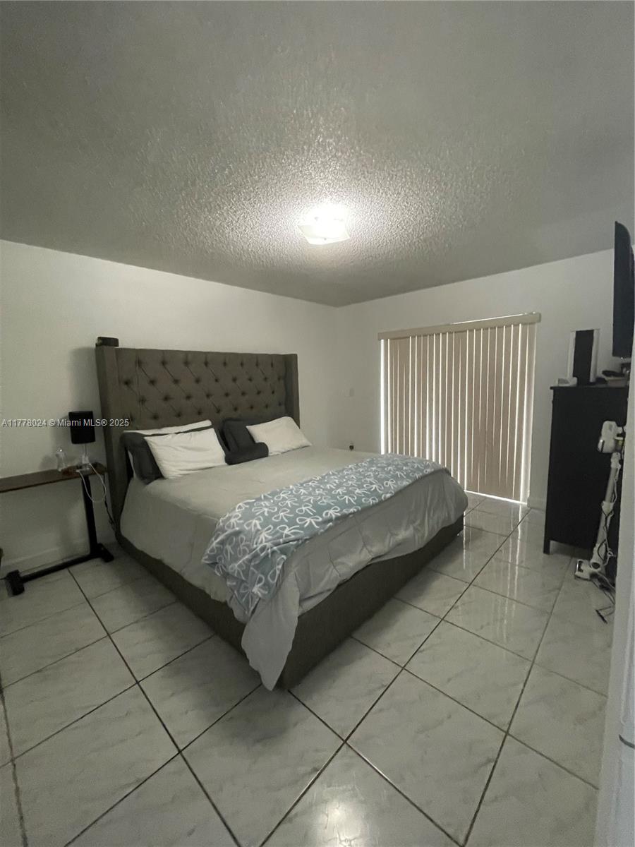 18230 Mediterranean Boulevard, Unit 1302 Hialeah, FL 33015 - Photo 4 of 42 a bedroom with a bed and a view of balcony