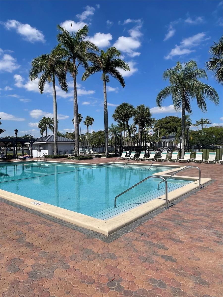 18230 Mediterranean Boulevard, Unit 1302 Hialeah, FL 33015 - Photo 41 of 42 a view of swimming pool with outdoor seating and palm tree