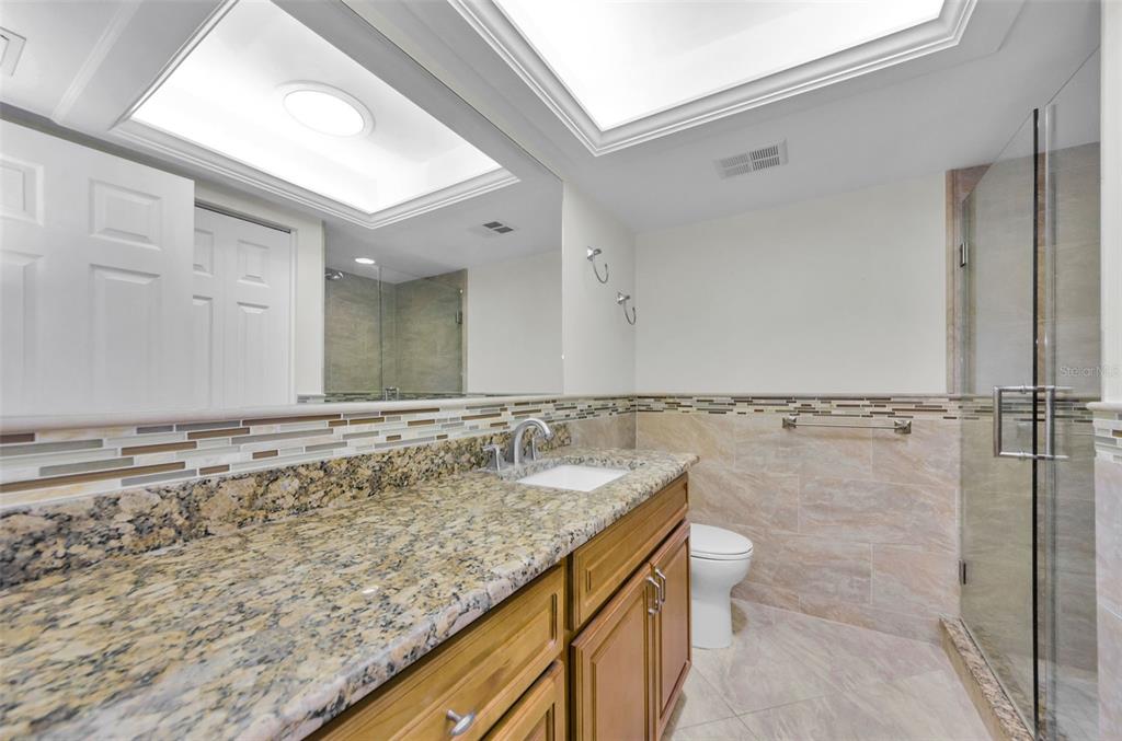 2836 Highlands Boulevard, Unit A Palm Harbor, FL 34684 - Photo 27 of 95 a bathroom with a granite countertop sink a mirror and bathtub