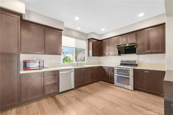 a kitchen with stainless steel appliances granite countertop wooden cabinets a stove top oven a sink and dishwasher