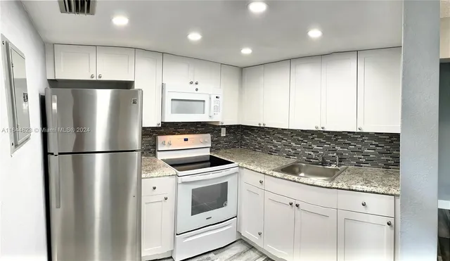 a kitchen with appliances a refrigerator and cabinets