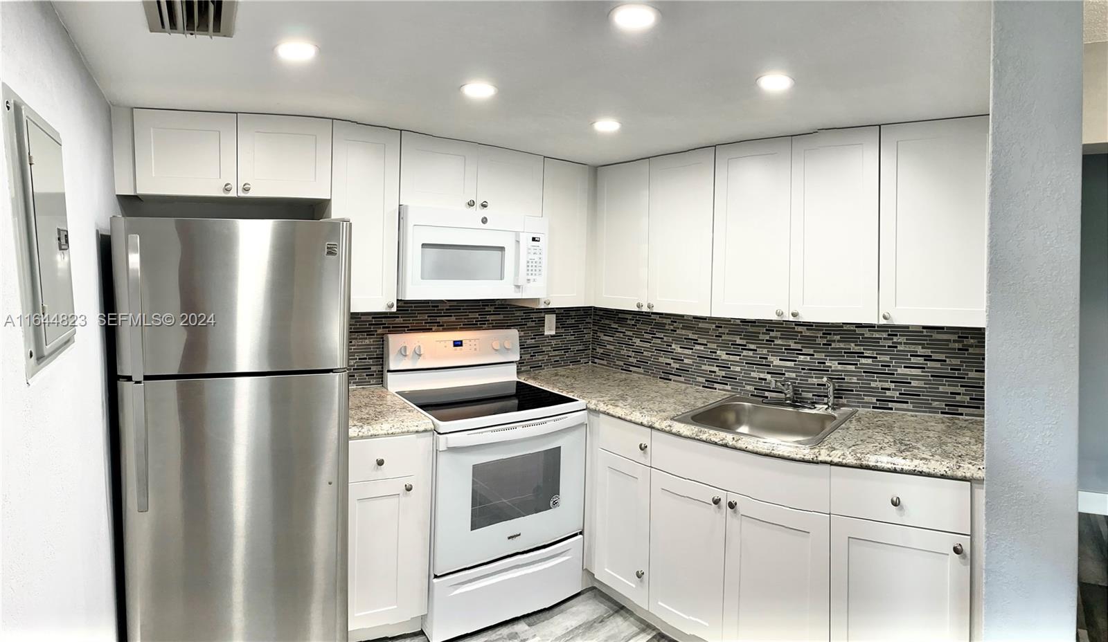 3075 Northwest 7th Street, Unit 302 Miami, FL 33125 - Photo 2 of 6 a kitchen with appliances a refrigerator and cabinets