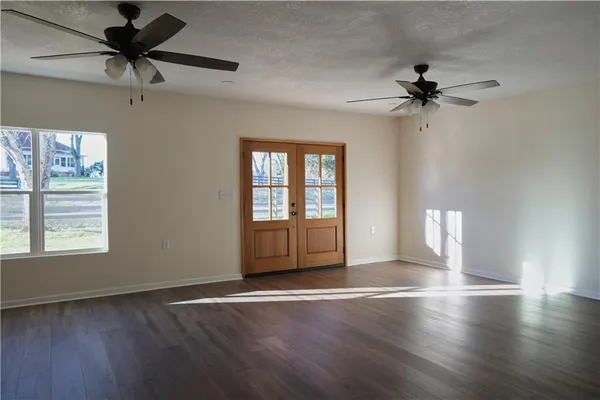 a view of an empty room with a window and wooden floor