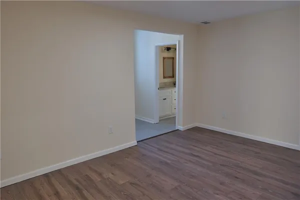a view of an empty room with wooden floor and closet