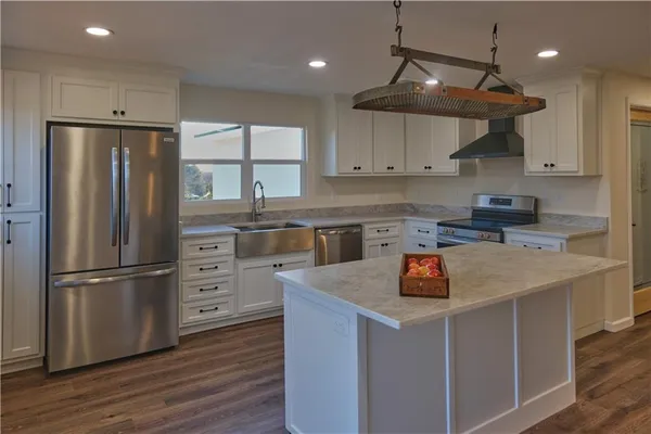 a kitchen with stainless steel appliances granite countertop a refrigerator a sink dishwasher a stove and a refrigerator with wooden floor