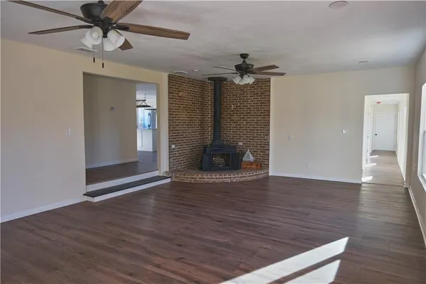 a view of empty room with wooden floor and ceiling fan