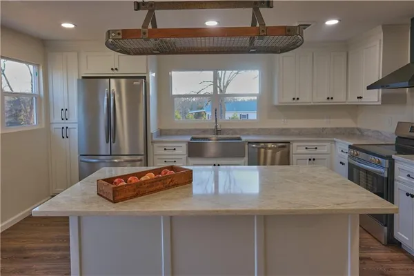 a kitchen with stainless steel appliances granite countertop a sink a microwave a refrigerator and white cabinets
