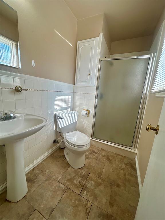 406 Northwest 5th Street Hubbard, TX 76648 - Photo 18 of 40 a white toilet sitting next to a bathroom sink and a shower