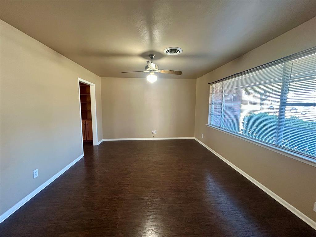 406 Northwest 5th Street Hubbard, TX 76648 - Photo 7 of 40 an empty room with wooden floor and windows with curtains