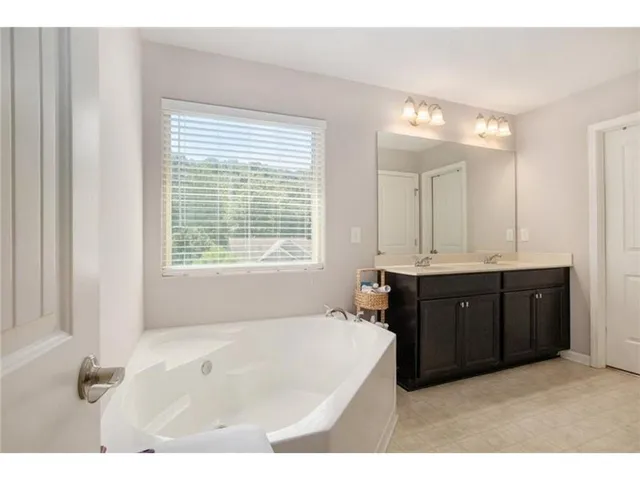 a spacious bathroom with a tub sink and mirror