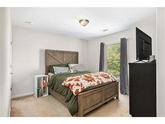 a bed sitting in a bedroom next to a window with a tv