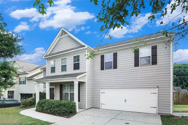 a view of a white house with a yard and potted plants