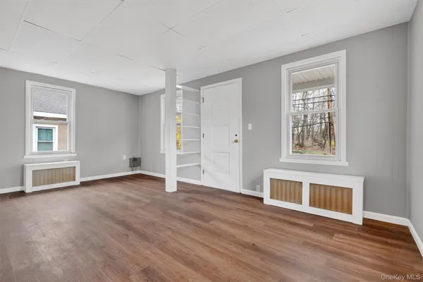 a view of an empty room with a window and wooden floor