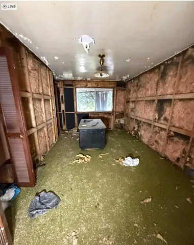 a living room with stainless steel appliances furniture a rug and a large window