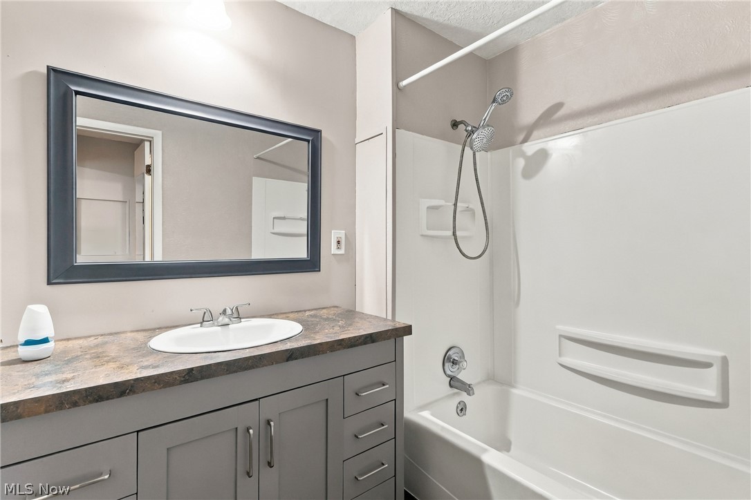 1875 Perth Road Madison, OH 44057 - Photo 30 of 48 Integrated bathtub and shower combination with white surround, vanity with dark countertop, undermount sink, and a framed rectangular mirror