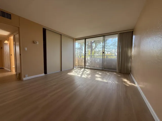 a view of empty room with wooden floor and fan