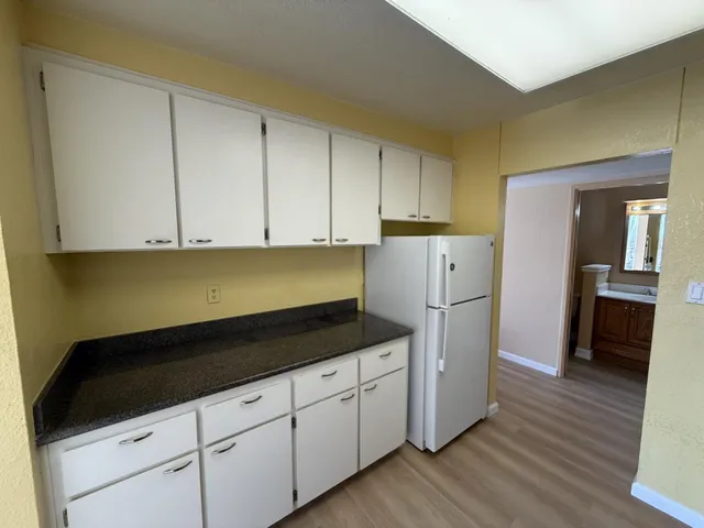 a kitchen with granite countertop white cabinets and refrigerator
