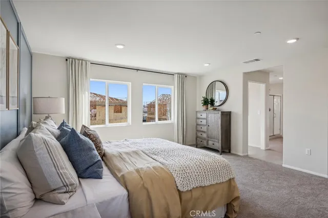 a spacious bedroom with a bed a closet and large mirror