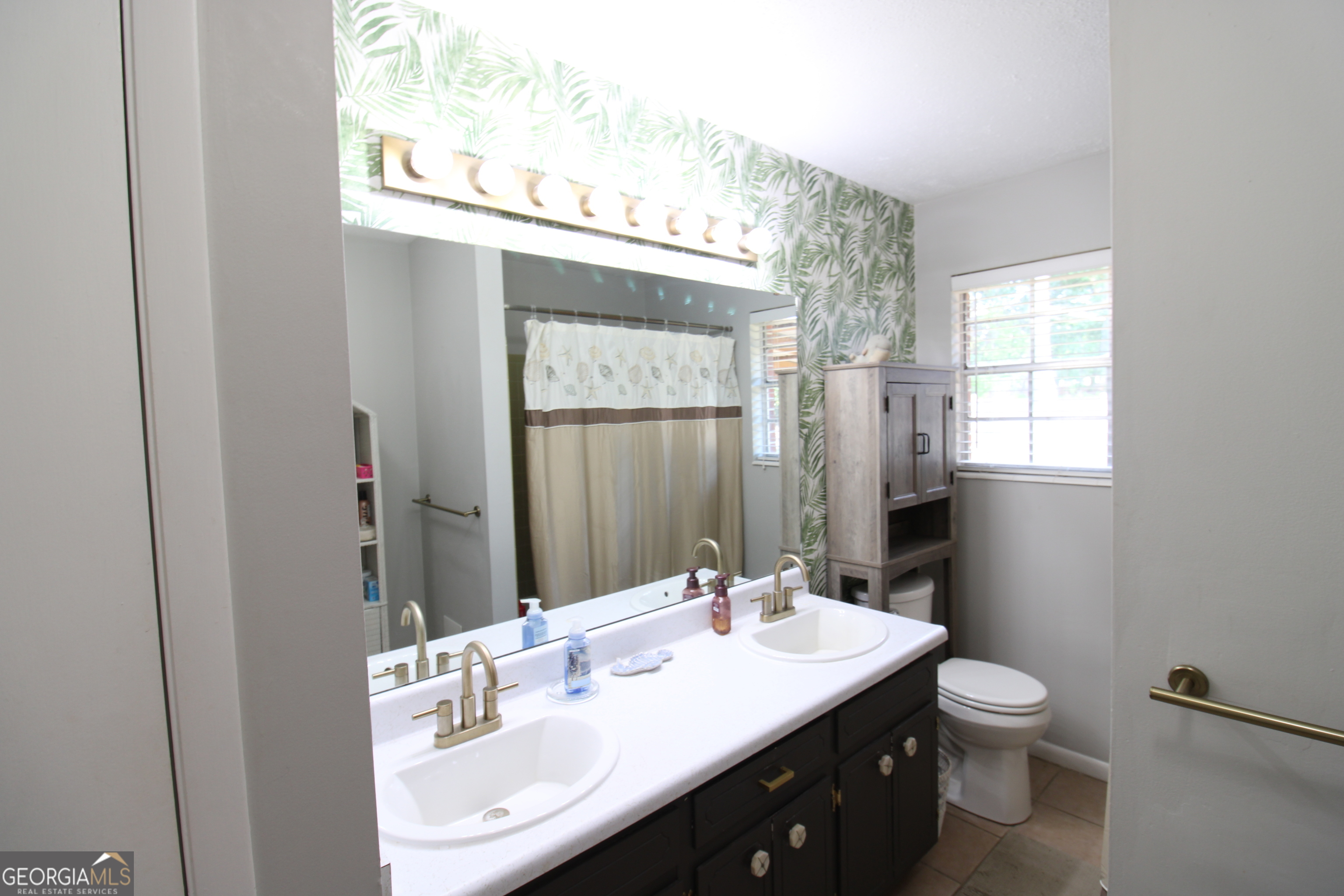 2337 Spring Street Waycross, GA 31503 - Photo 18 of 28 a bathroom with a granite countertop sink toilet a large mirror and a window