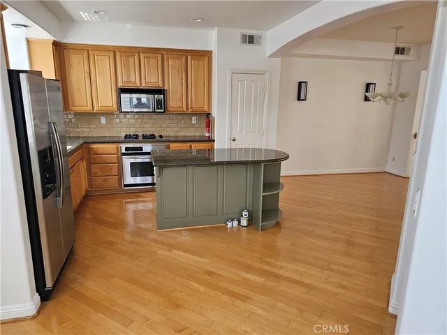 a kitchen with granite countertop a refrigerator a stove top oven a sink and dishwasher